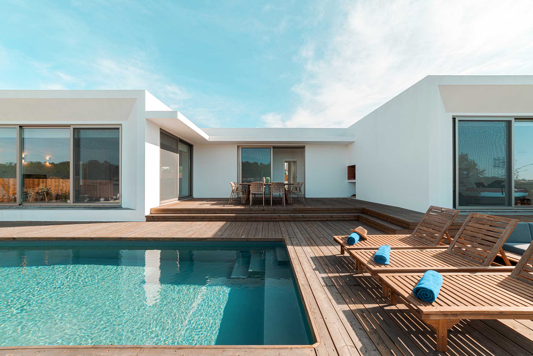 Wooden lounge chairs in modern villa pool and deck